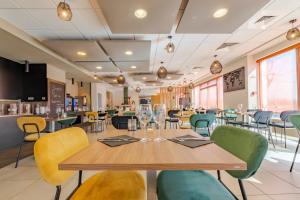 een restaurant met een houten tafel en stoelen bij Mandarina Hotel Luxembourg Airport in Luxemburg