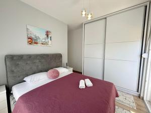 een slaapkamer met een bed met een paarse deken en witte kussens bij Era Apartments in Ulcinj +30 foto's
