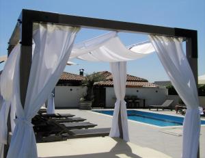 a white canopy over a swimming pool next to a house at Božikovina Beach Rooms in Podstrana