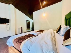 1 dormitorio con 2 camas y TV en la pared en Hotel Sliver Inn - Affordable Luxury Stay Near Mall Road en Manāli