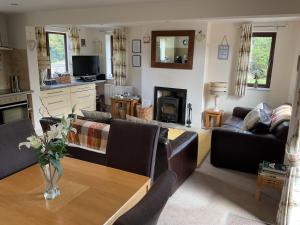 a living room with couches and a wooden table at Woodside Cottage in Ripon