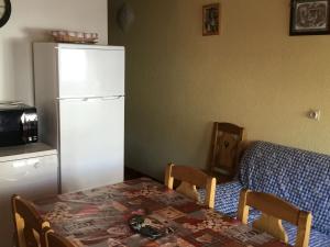 une cuisine avec une table et un réfrigérateur blanc dans l'établissement Appartement 3 pièces avec balcon, proche des remontées mécaniques et du centre, parking inclus - FR-1-676-56, à Châtel