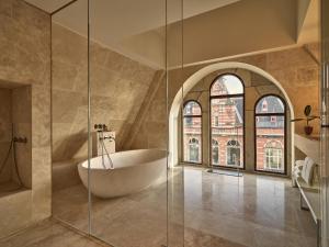 uma casa de banho com uma banheira e um chuveiro em vidro. em Conservatorium Hotel em Amesterdão