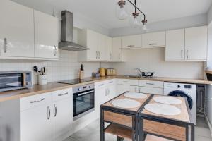 a kitchen with white cabinets and a wooden table at Niche Sunrise Townhouse in Chelmsford