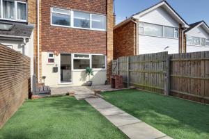 a small backyard with a fence and grass at Niche Sunrise Townhouse in Chelmsford
