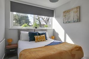 a bedroom with a bed with pillows and a window at Niche Sunrise Townhouse in Chelmsford