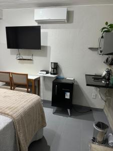 sypialnia z łóżkiem i biurkiem z telewizorem w obiekcie Chalé 01 com hidro e cozinha no coração de Penedo w mieście Itatiaia