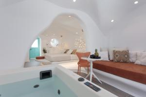 Sala de estar blanca con sofá y mesa en Naxos Cave Suites, en Stelida