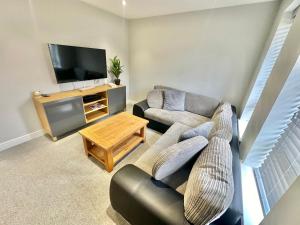 a living room with a couch and a tv at Stylish Coastal Retreat with Garden, Hot Tub and Gas BBQ in Bournemouth
