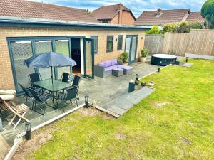 a patio with a table and chairs and an umbrella at Stylish Coastal Retreat with Garden, Hot Tub and Gas BBQ in Bournemouth