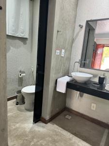 uma casa de banho com um WC, um lavatório e um espelho. em Chalé 01 com hidro e cozinha no coração de Penedo em Itatiaia