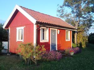 une petite maison rouge et blanche dans l'herbe dans l'établissement Cozy cottage in Aleklinta, north of Borgholm, close to the sea, à Borgholm