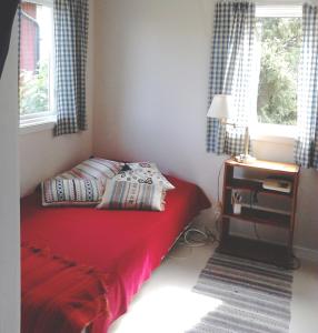 - une chambre avec un lit rouge et une table de nuit dans l'établissement Cozy cottage in Aleklinta, north of Borgholm, close to the sea, à Borgholm