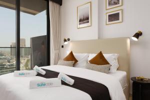 two beds in a hotel room with a window at Experience Serenity at Binghatti Crest in JVC in Dubai
