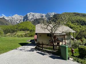 a small house with a fence and mountains in the background at Apartma Žagar Robert in Log pod Mangartom +12 photos