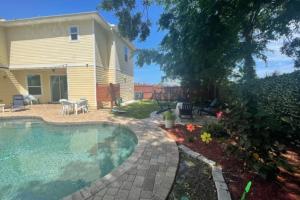 un patio trasero con piscina y una casa en Relax in Jax en Jacksonville Beach