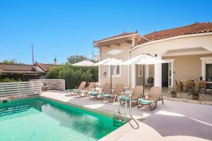 a house with a swimming pool with chairs and umbrellas at Villa Meredith by Villa Plus in Psarou