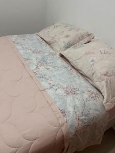 Una cama blanca con una manta floral. en Ap 2 quartos climatizados 5min Praia de BC acesso as Praias, en Camboriú