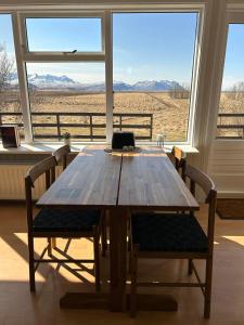 una mesa de madera y sillas en una habitación con ventana en The Hvítá Inn en Bær