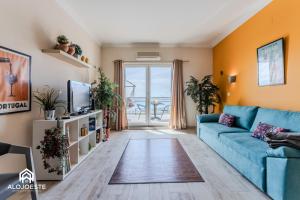 a living room with a blue couch and a tv at Ocean Paradise - Apartment with ocean view in Ericeira