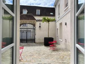 a view from a window of a courtyard with red chairs at Le Laurencin Sens - La Verrière in Sens