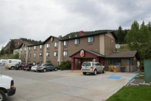 un grand bâtiment avec des voitures garées dans un parking dans l'établissement Super 8 by Wyndham Williams Lake BC, à Williams Lake