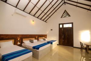 a bedroom with two beds and a table and a door at Ari Guest House in Anuradhapura