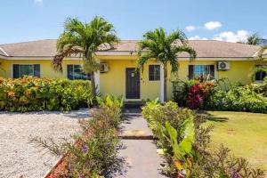 ein gelbes Haus mit Palmen im Hof in der Unterkunft Tropicabana in Nassau