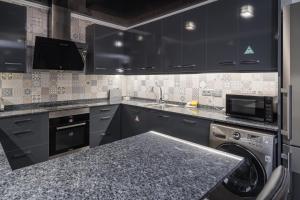 a kitchen with black cabinets and a sink and a dishwasher at GuestReady - Living a dream in Barcelona in Barcelona