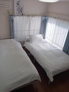 2 camas en un dormitorio con sábanas blancas y ventana en Tokyo downtown, en Tokio