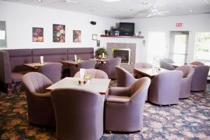 a restaurant with tables and chairs and a fireplace at Country Club Inn in Lacombe