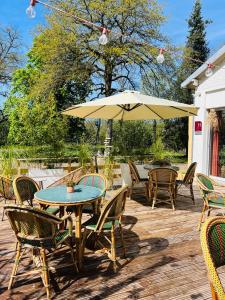 un patio con mesas, sillas y una sombrilla en Motel Les Broussailles, en Mesves-sur-Loire
