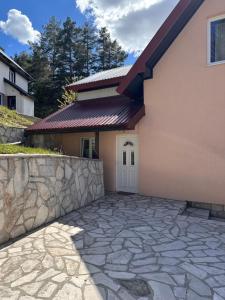a house with a stone driveway in front of it at Guest House Dzakovic Stana in Žabljak