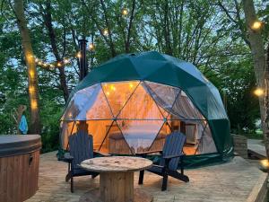 a tent with chairs and a table in front of it at La Ferme 1851 - Cabane Spa Nordique privé vue sur champ in Willems