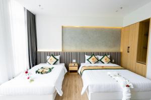 2 letti in una camera con lenzuola e cuscini bianchi di TRẠNG NGUYÊN HUẾ HOTEL a Hue