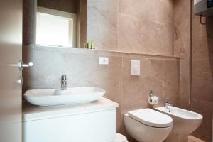 a bathroom with a sink and a toilet and a mirror at Green Coast Resort and Residences in Palasë