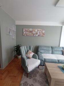 sala de estar con sofá azul y silla en Apartman Dragon Kg en Kragujevac