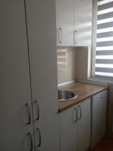una pequeña cocina con fregadero y armarios blancos en Apartman Dragon Kg en Kragujevac