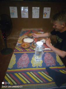 a man sitting at a table with food on it at Vihanga Guest House in Habarana