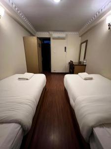 two beds in a hotel room with white sheets at Taleju Grand Hotel in Bhaktapur
