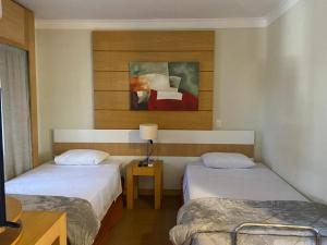 a room with two beds and a painting on the wall at Suite dupla ao lado do aeroporto de Congonhas in Sao Paulo