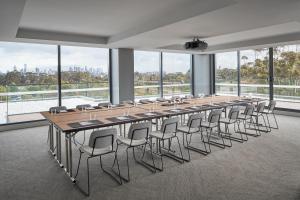 a long table and chairs in a room with windows at Element Melbourne Richmond in Melbourne