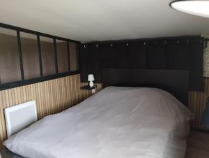 ein Schlafzimmer mit einem weißen Bett mit einem schwarzen Kopfteil in der Unterkunft La Rose du Bel Homme in Rocroi