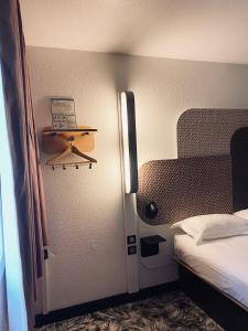 a small room with a bed and a laptop on a shelf at B&B HOTEL Montpellier Sud Lattes in Lattes