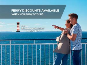 a man and woman standing on a cruise ship with a lighthouse at The Beach Retreat - Pet Friendly in Sandown