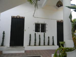 a white wall with black doors and a fence at Casa Vista Al Mar - Iguana Room in Puerto Escondido +2 photos