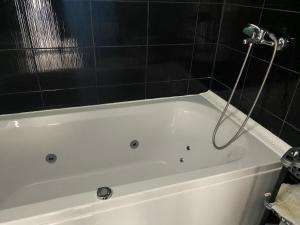 a white bath tub in a bathroom with black tiles at Ferienhaus in Strandnähe in Shabla