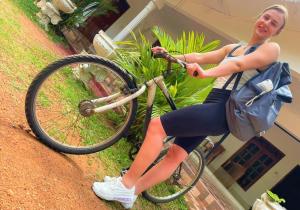 Eine Frau, die mit einer Tasche auf einem Fahrrad sitzt. in der Unterkunft Grand Refuge Holiday Rooms in Anuradhapura