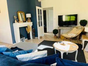 een woonkamer met een bank en een tv bij Le 4 Maison de charme proche de la plage wifi in Barneville-Carteret