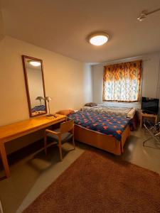 een slaapkamer met een bed, een bureau en een spiegel bij Grand Hostel Imatra in Imatra